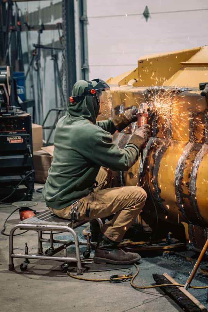 Welding technician working on heavy machinery at Wesco Machine Works.