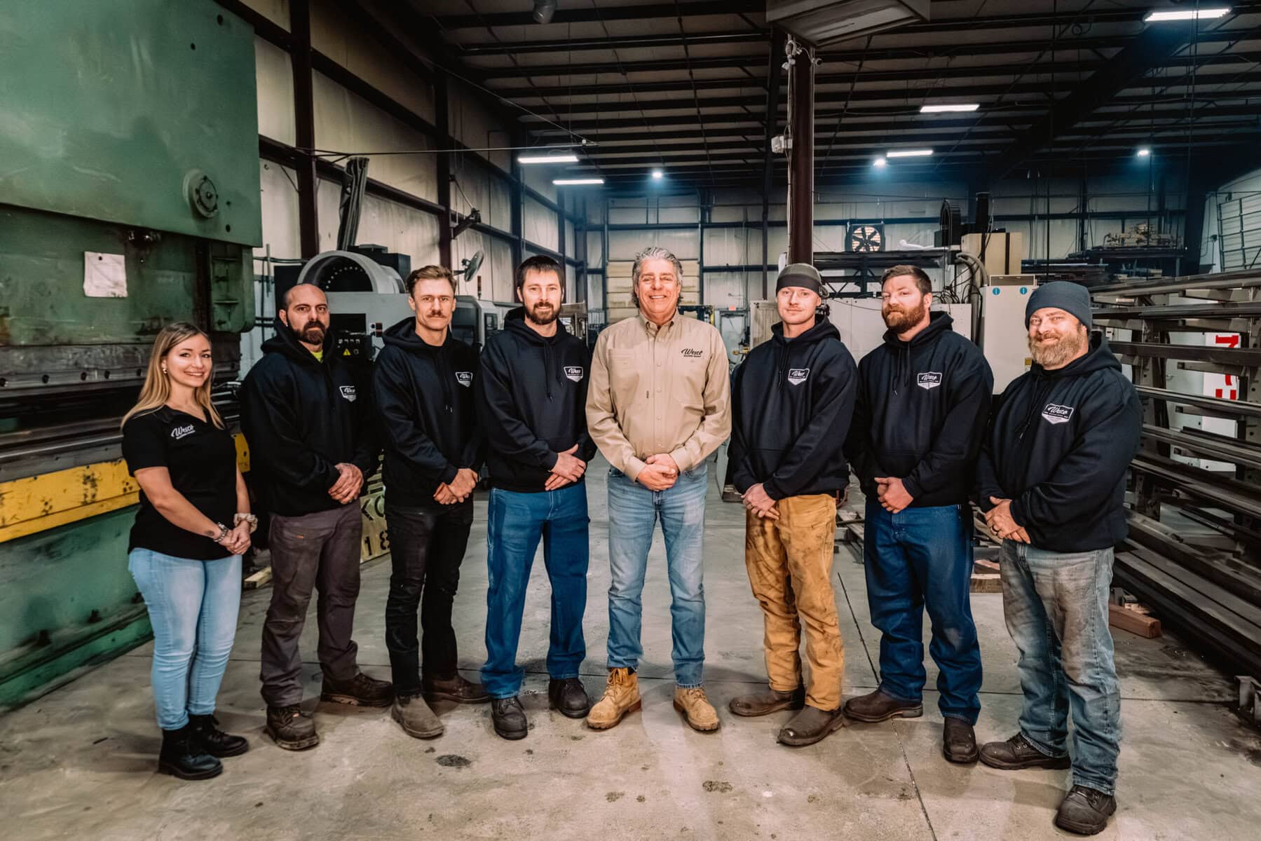 Group of employees at Wesco Machine Works in industrial workshop setting.