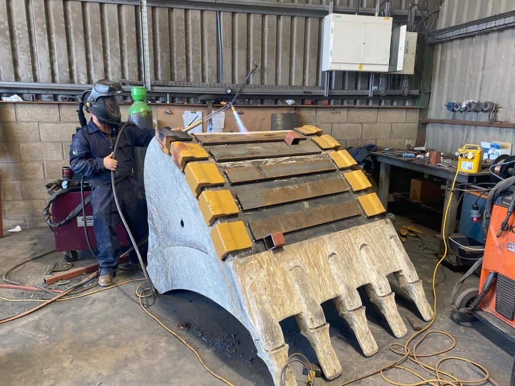 Heavy-duty excavator bucket being welded at Wesco Machine Works.